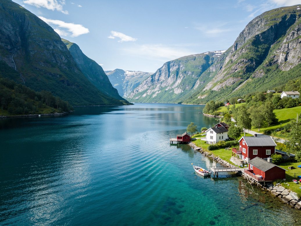 Fjordlandskap med røde hus og fjell i bakgrunnen